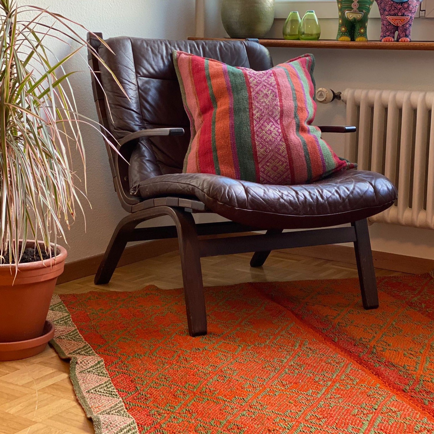 Vintage Ledersessel mit farbigem peruanischen Kissen und buntem Teppich, orange