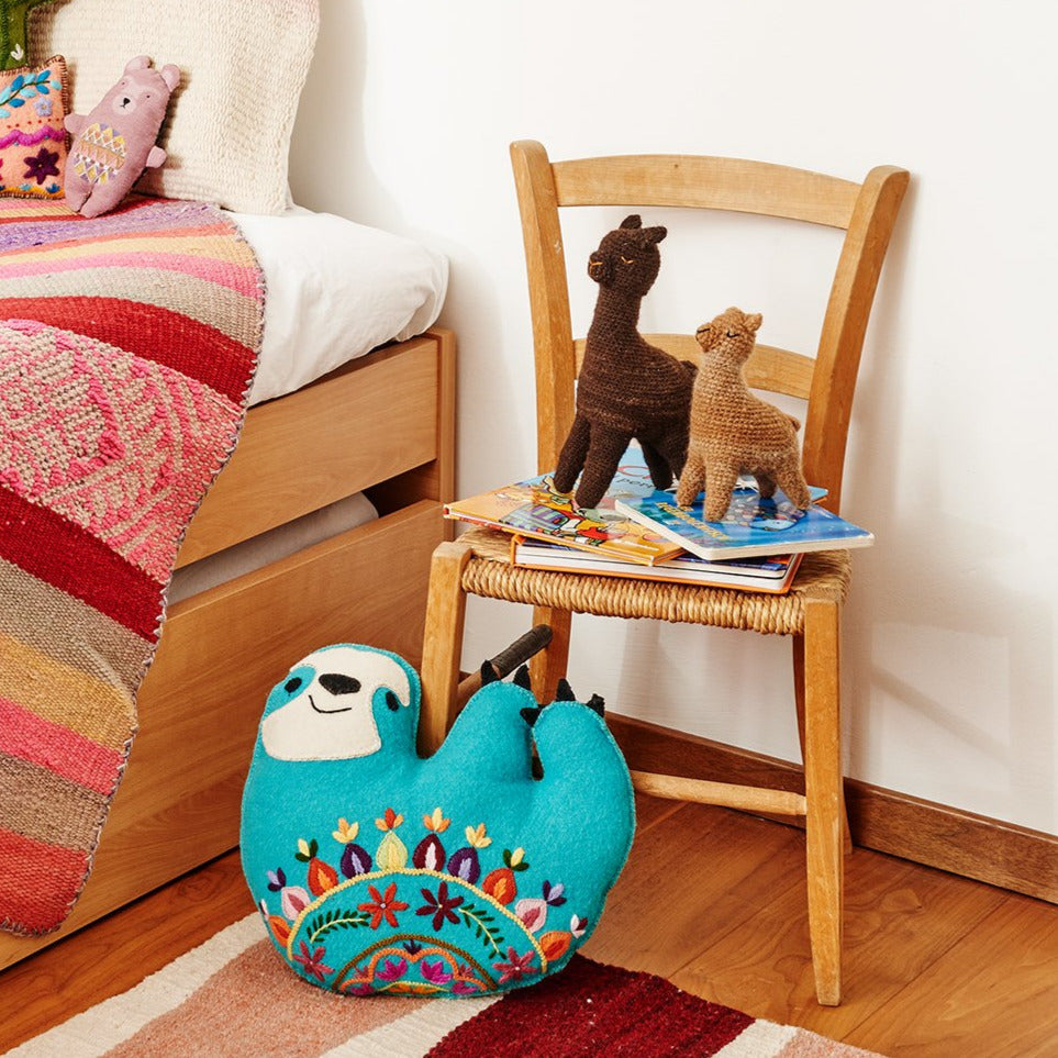 zwei von Hand gehäkelte braune Lamas aus Alpacawolle auf einem Stuhl