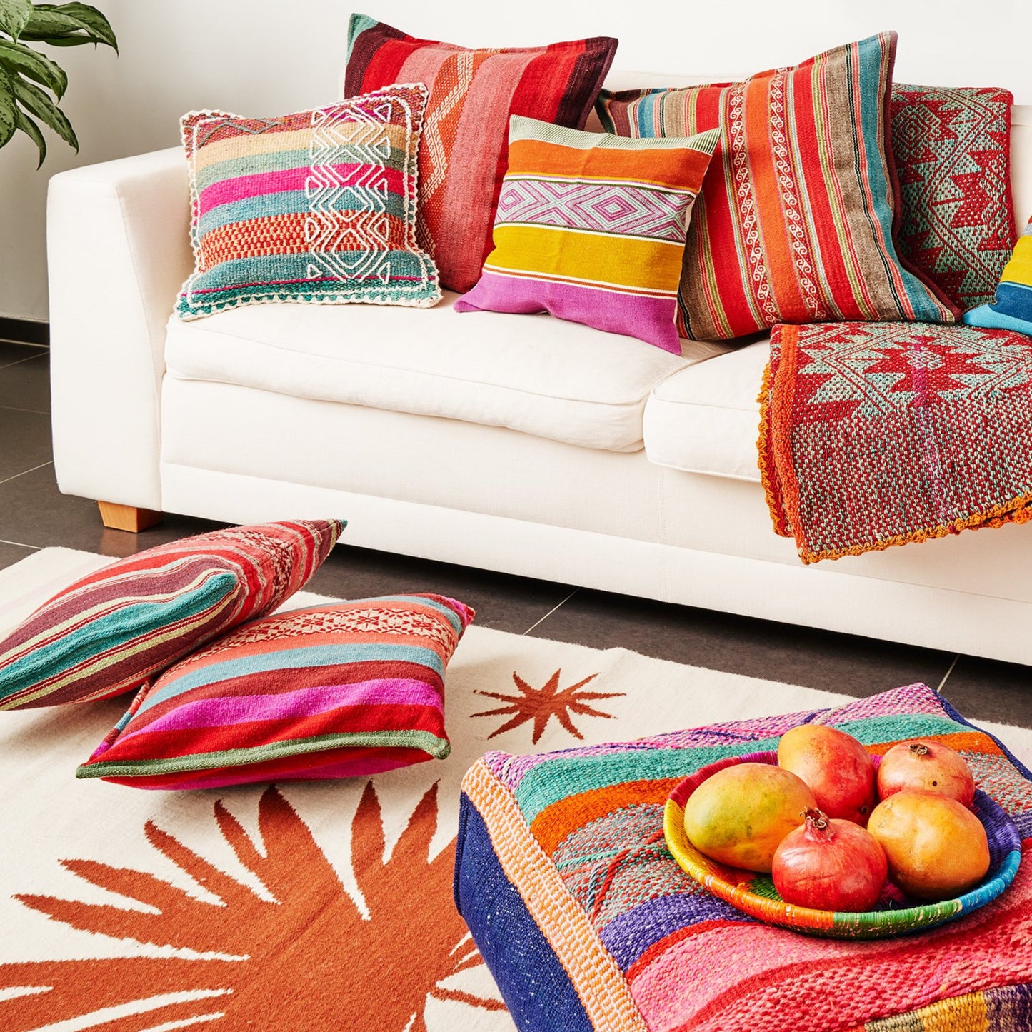 Farbige Kissen aus Peru auf Sofa mit PUNA Teppich und von Hand gewobenem Pouff.