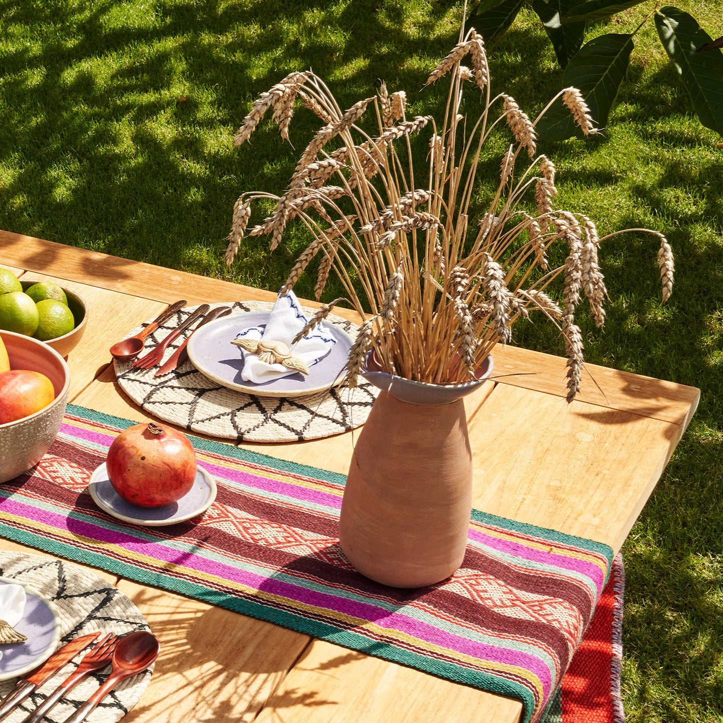 Gedeckter Tisch in Wiese mit Krug mit Trockenblumen