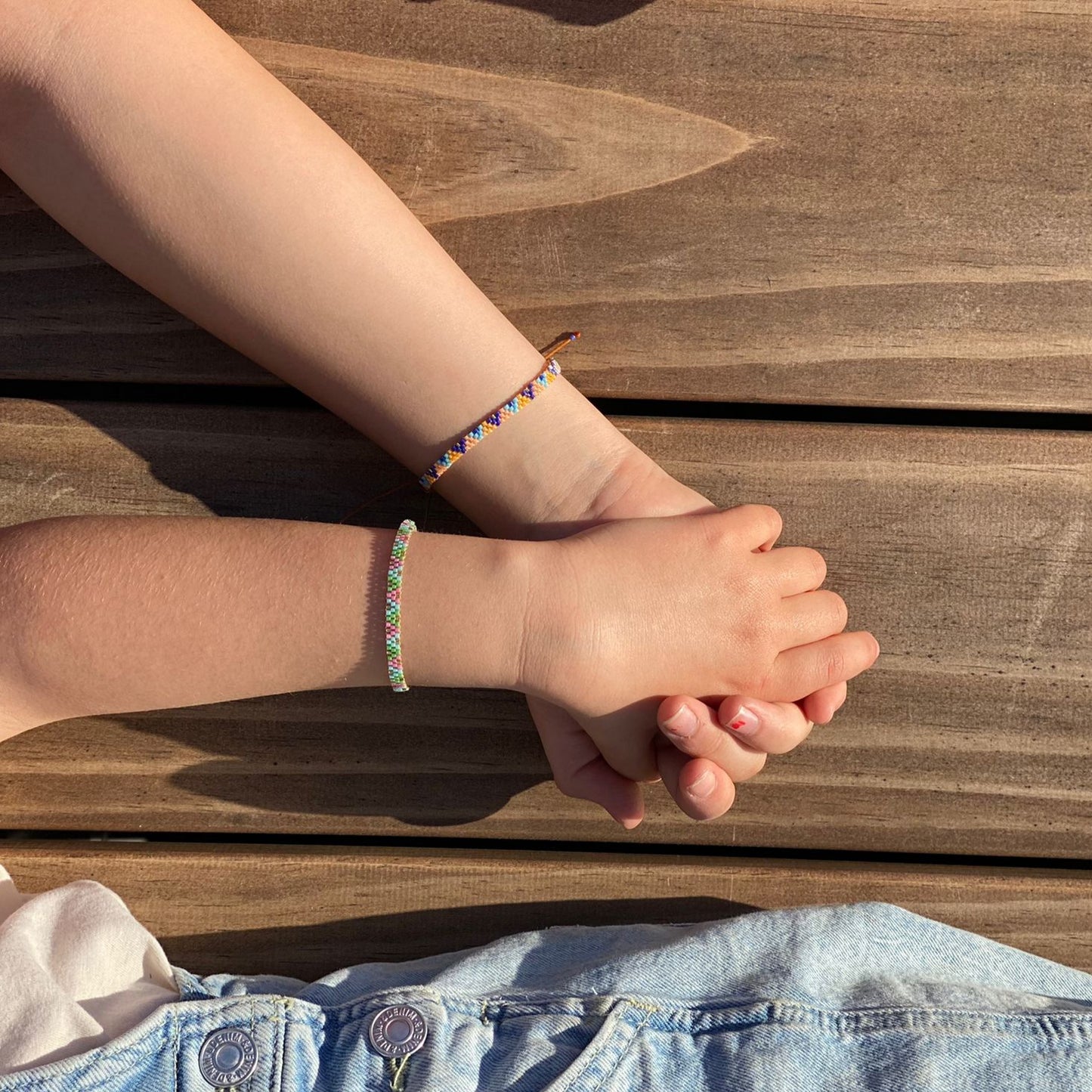 zwei Kinder tragen peruanische Armbändchen aus Miyuki Perlen und halten sich an den Händen