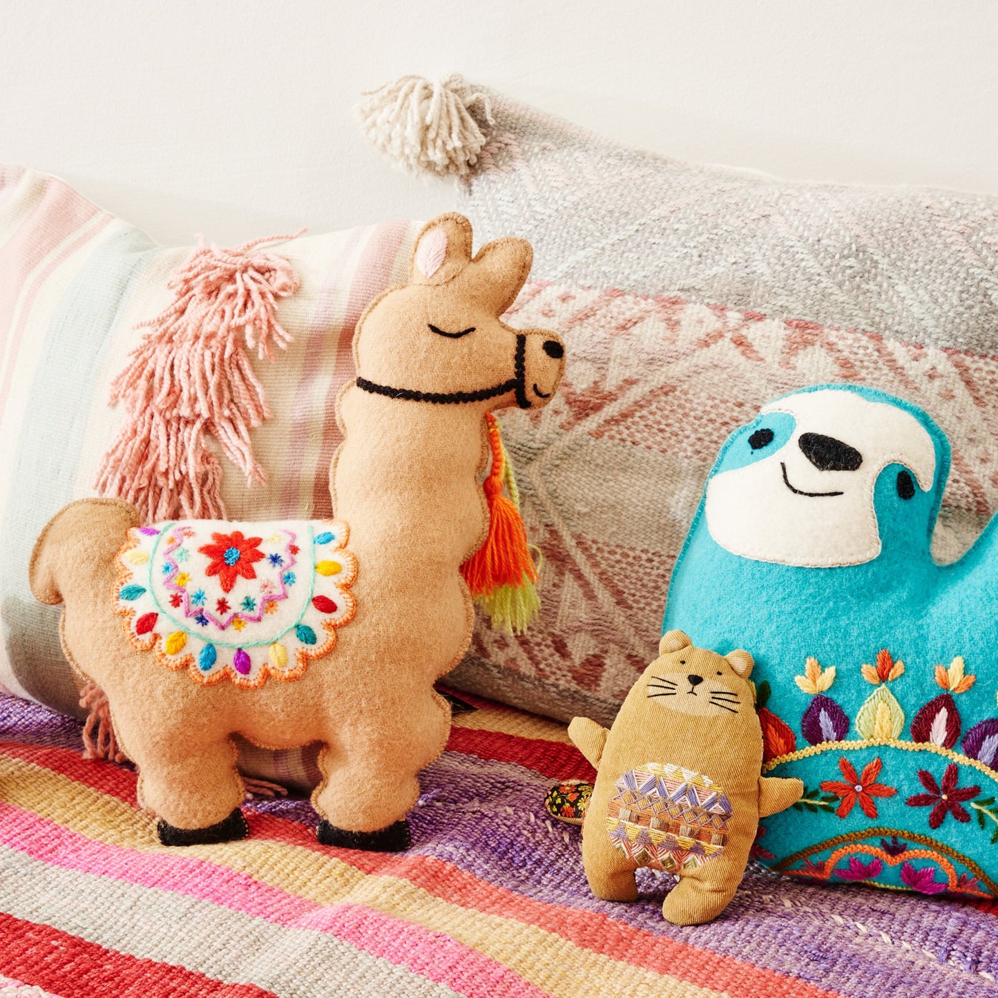 Bett mit farbiger Decke und Kissen und Stofftieren, Lama, Faultier und Fischotter
