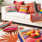 Farbige Kissen aus Peru auf Sofa mit Teppich und Pouff. 
