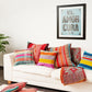 weisses Sofa mit grossen und kleine farbigen Kissen und blauem Bild an der Wand