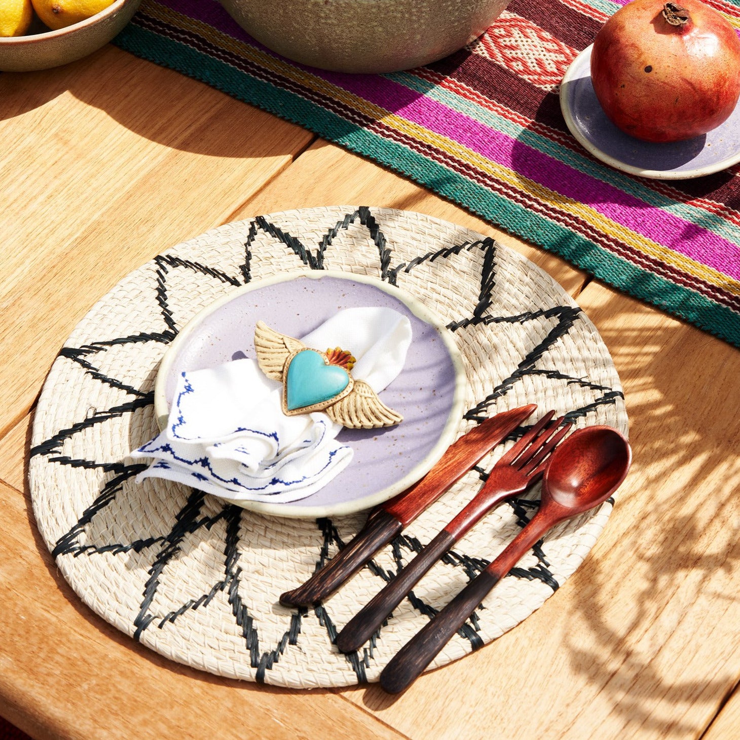 rundes Tischset mit violettem Keramik Teller und Holzbesteck.