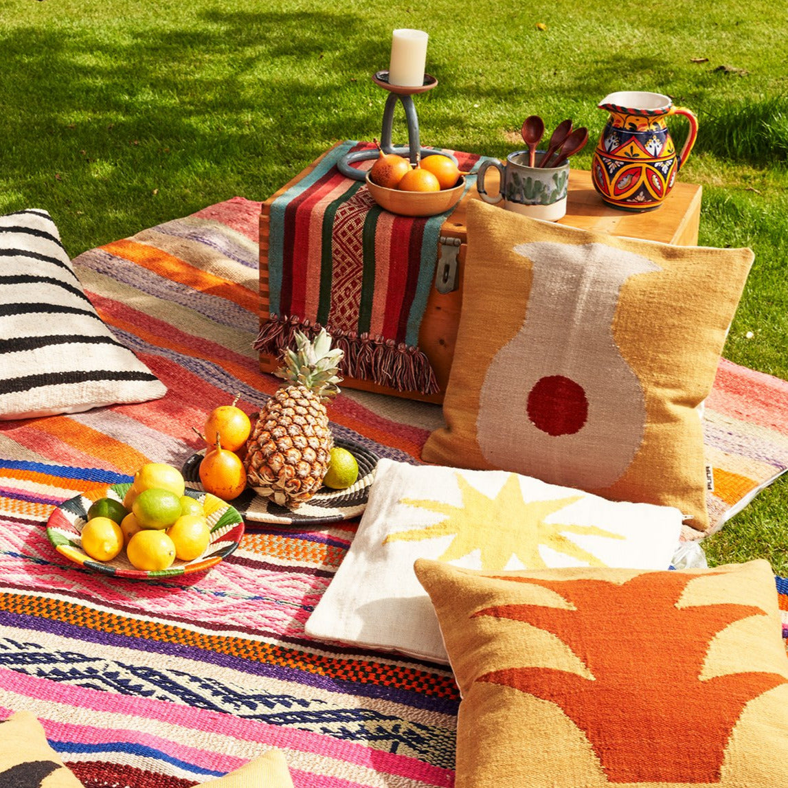 Farbiges Picknick mit peruanischen Kissen, Teppichen und Früchten