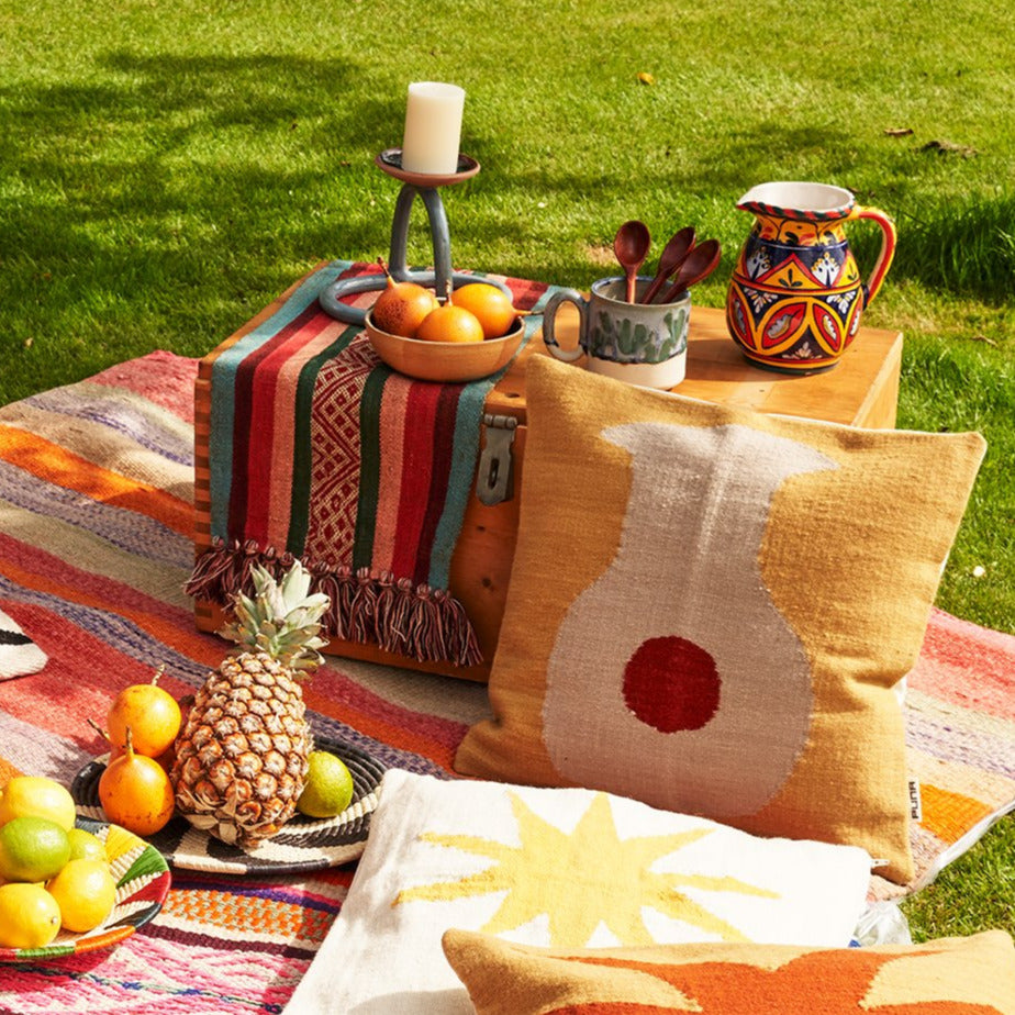 Picknick auf Wiese mit Früchteschalen, farbigen Decken und Kissen