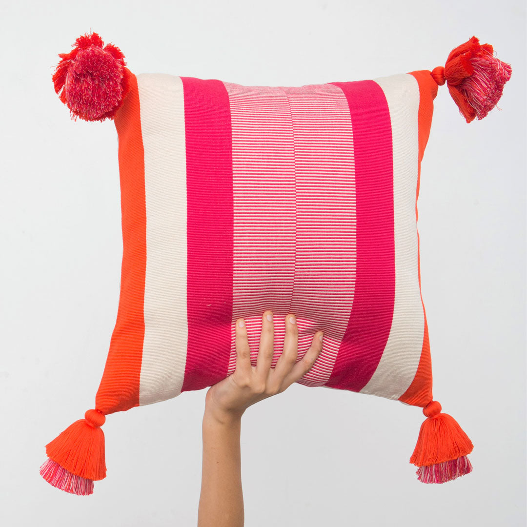 Von Hand gewobenes Kissen mit modernem pink und orangem Linienmuster und mit Tasseln.
